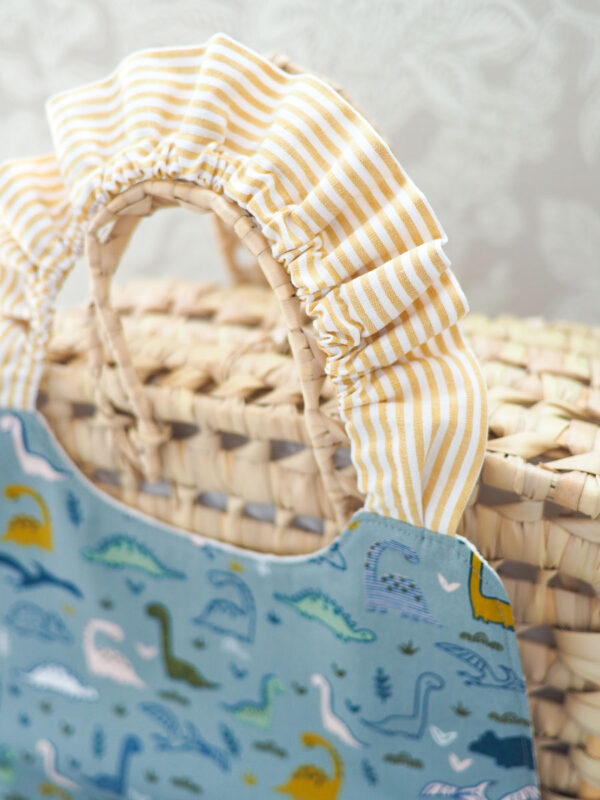 Serviette élastique pour enfant "Les Dino" avec motif coloré de dinosaures, taille adaptée aux 2-6 ans, en coton doux et nid d’abeille absorbant.